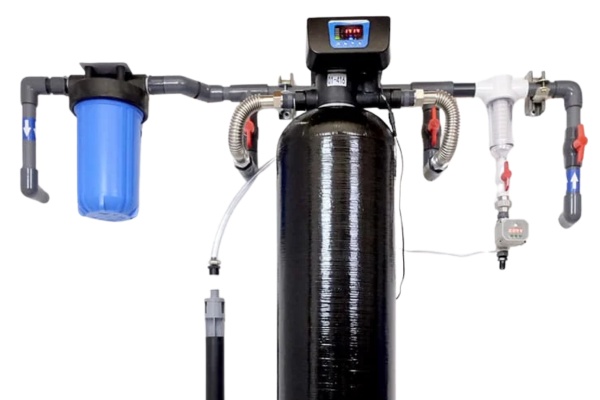 Pro-OX Iron Filter 7500-M system installed with connected plumbing, featuring a digital control valve, black mineral tank, blue pre-filter housing, white spin-down filter, and flow meter.