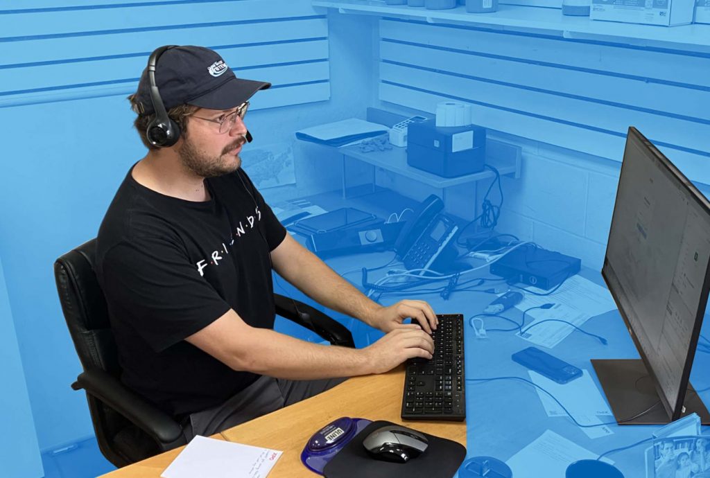 A Clean Water Store support representative wearing a headset and typing on a computer, providing expert water treatment guidance.