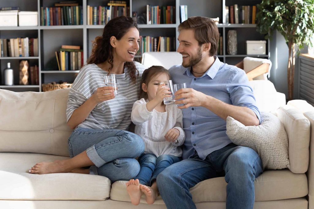 Family of three on couch drinking purified water.