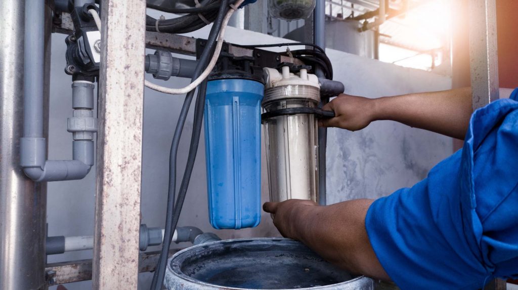 Man changing out water filters for well water treatment system.