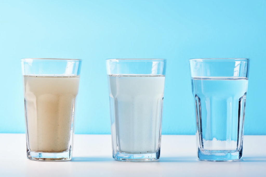 Water Glasses filled with water, sediment and cloudy and one clean, showing after water filtration results.