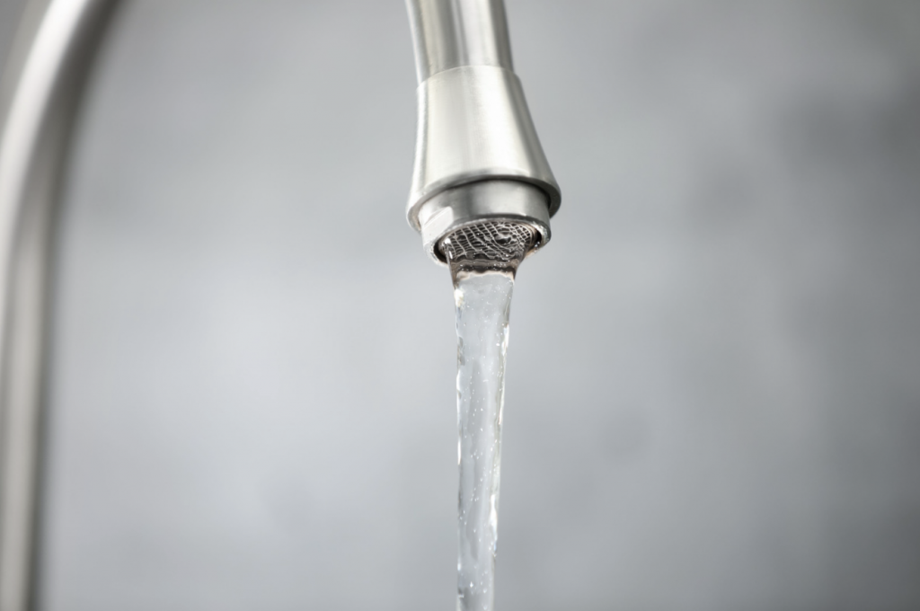 Tap water coming out at a low water pressure in kitchen sink faucet.
