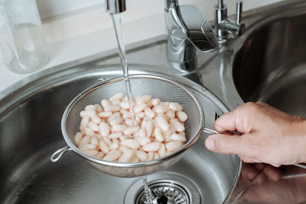 Rinsing beans with tap water in kitchen sink.