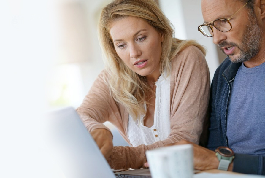 Shows two homeowners looking at their computer and deciding on what they need to buy to complete their home water treatment design.