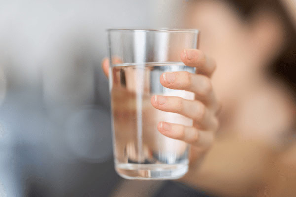Woman holding up a glass of clean water.
